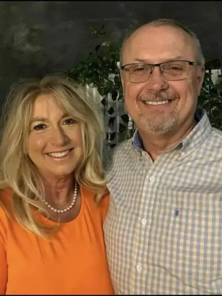 Man and woman stand smiling close together 