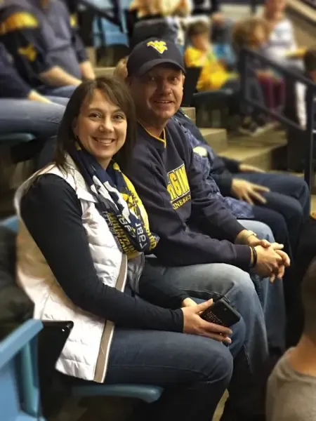 Kristi Norris and husband sitting at stadium dressed in WVU apparel